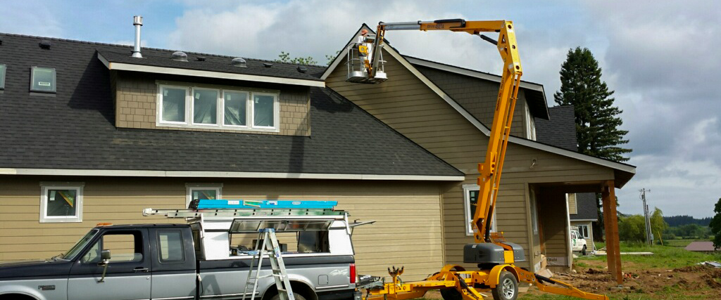 Reaching heights to paint a house with a lift.